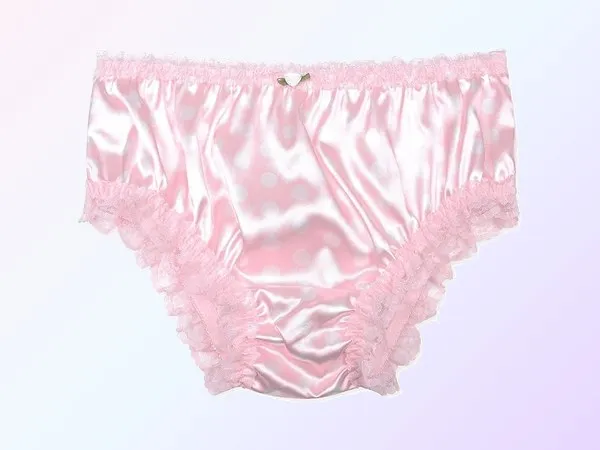 A pair of baby pink satin knickers laid flat, ruffled lace at the waistband and around both legs, a tiny bow at the front, on a soft pink and lavender gradient.